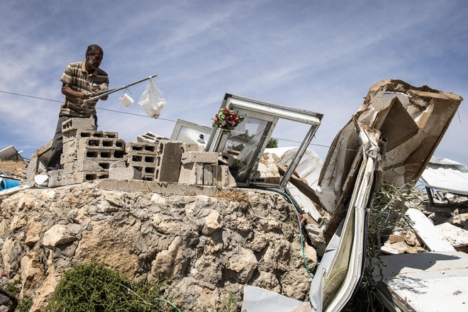 A Palestinian collects salvaged items the rubble of a demolished home in the village of Khallet Al Dabaa in the Masafer Yatta area in the occupied West Bank on May 6, 2025, after Israeli forces destroyed ninety-five percent of all the houses displacing around one hundred people (AFP photo)